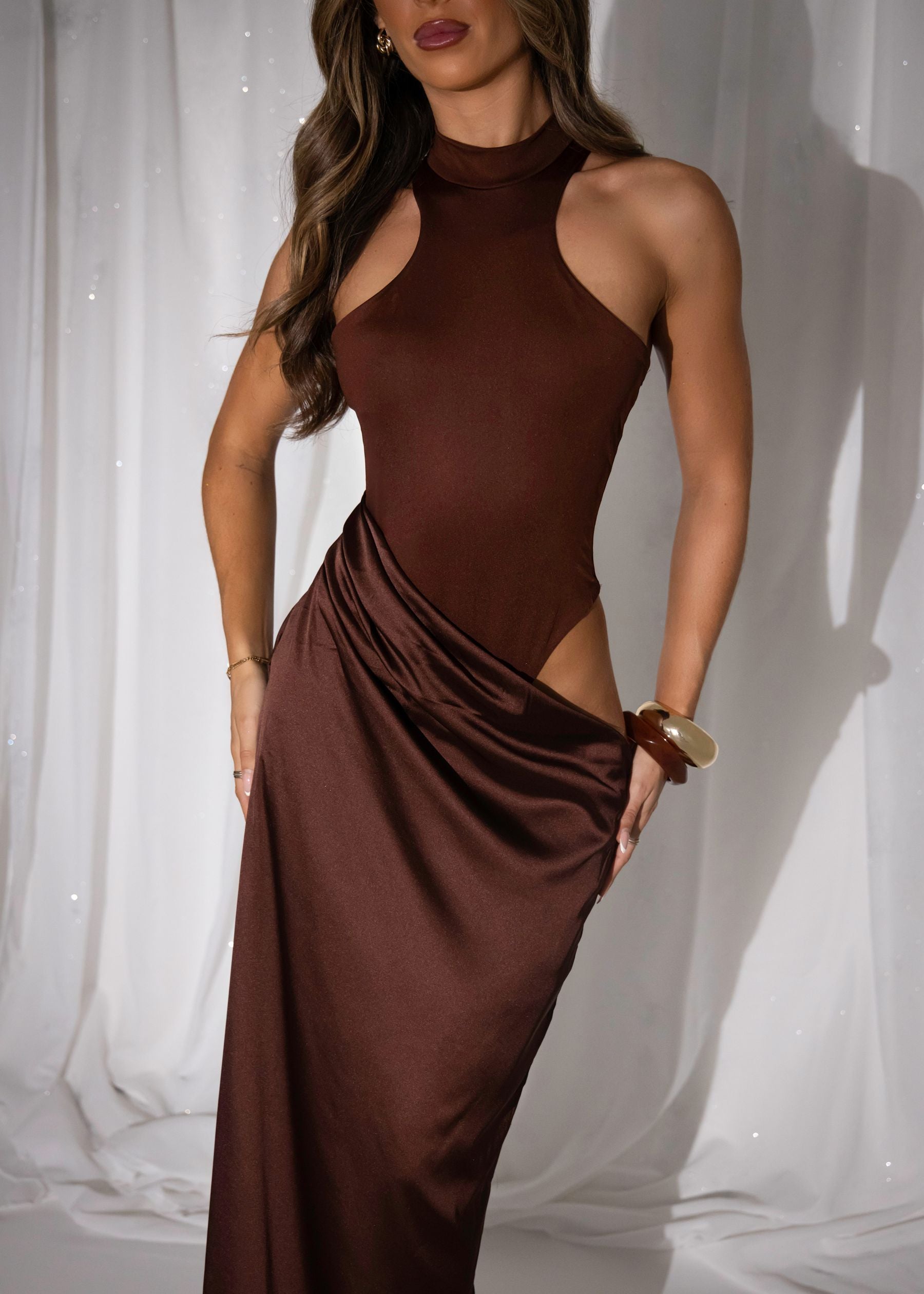 Women's brown maxi dress with built in brown bodysuit and racer style neckline and satin skirt starting at waistline. Cut out detail on the thigh and maxi length skirt.